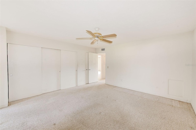 unfurnished bedroom featuring light carpet, ceiling fan, and a closet