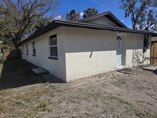 view of home's exterior with fence and stucco siding