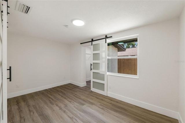 8319 N 14th St, Tampa, FL 33604 - unfurnished room with a barn door, baseboards, wood finished floors, and a smoke detector