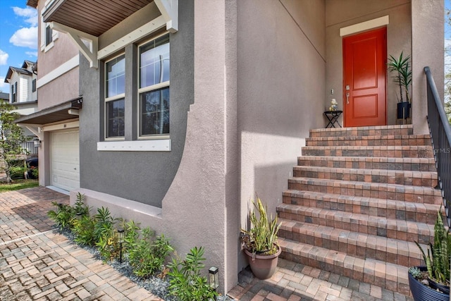 doorway to property featuring decorative driveway and stucco siding