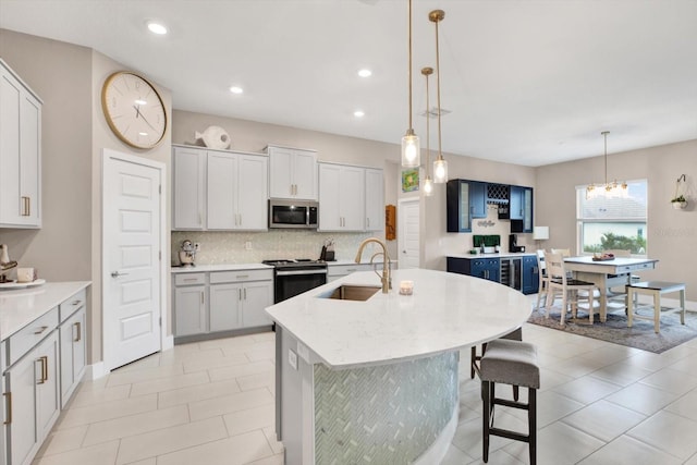 kitchen with a center island with sink, range with electric stovetop, tasteful backsplash, stainless steel microwave, and a sink