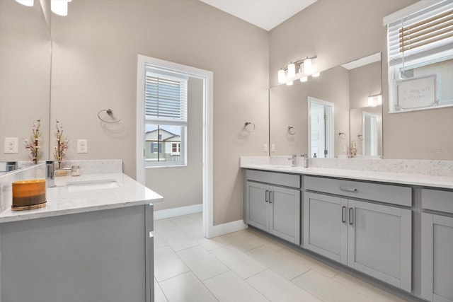 bathroom with baseboards, two vanities, and a sink