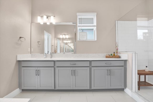 full bathroom with a tile shower, vanity, baseboards, and tile patterned floors