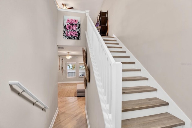 staircase with ceiling fan, wood finished floors, a towering ceiling, visible vents, and baseboards