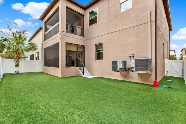 back of property with stucco siding, a yard, and central air condition unit