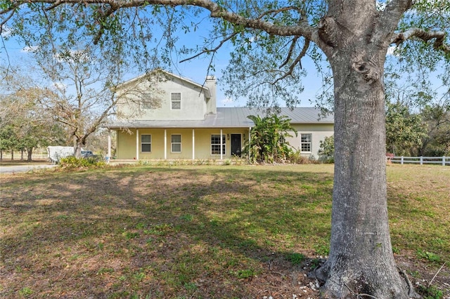 view of front of property featuring a front yard, fence, a standing seam roof, stucco siding, and metal roof