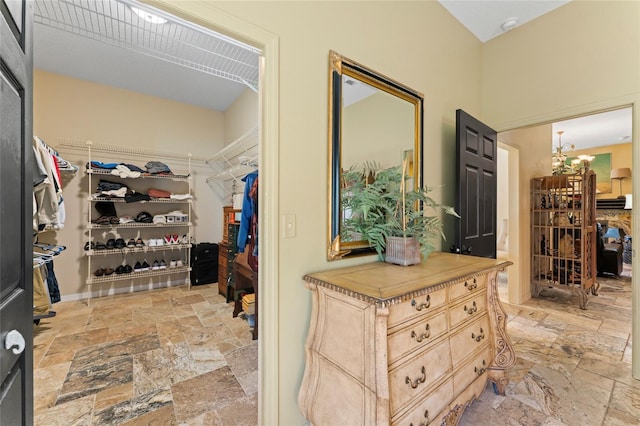 spacious closet featuring stone tile floors and a notable chandelier