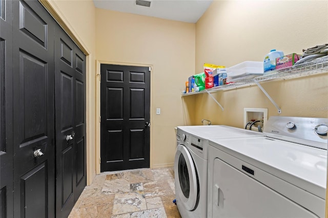 washroom with washer and dryer, laundry area, visible vents, and stone finish flooring