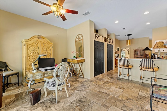 kitchen with visible vents, a breakfast bar area, a peninsula, stone finish floor, and a ceiling fan