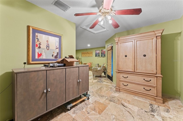 interior space with stone finish flooring, a ceiling fan, visible vents, and baseboards