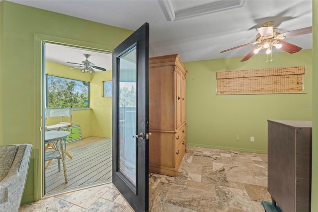 interior space with stone tile floors, baseboards, a textured ceiling, and ceiling fan