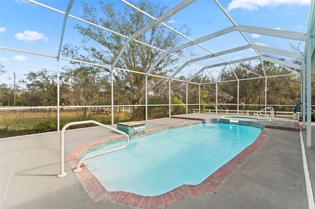 view of pool featuring a patio area, glass enclosure, and a pool with connected hot tub