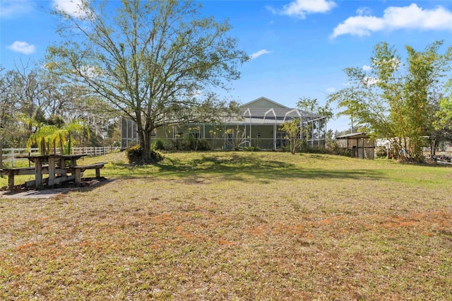 view of yard with glass enclosure and fence