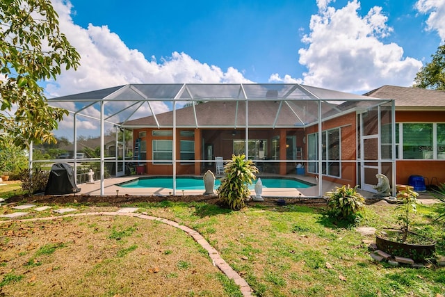 back of property featuring glass enclosure, a yard, a patio area, and an outdoor pool