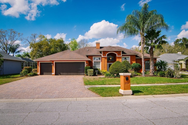 single story home with a chimney, a garage, decorative driveway, a front lawn, and stucco siding