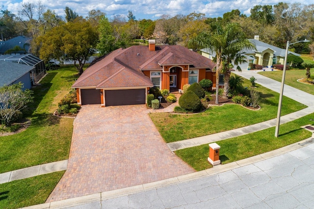 view of front facade with a garage, decorative driveway, a front lawn, and a chimney