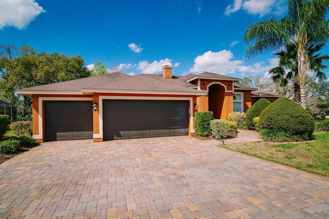 ranch-style home featuring a garage, a chimney, stucco siding, and decorative driveway