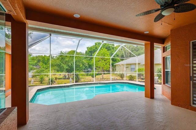 pool with a ceiling fan, glass enclosure, and a patio area