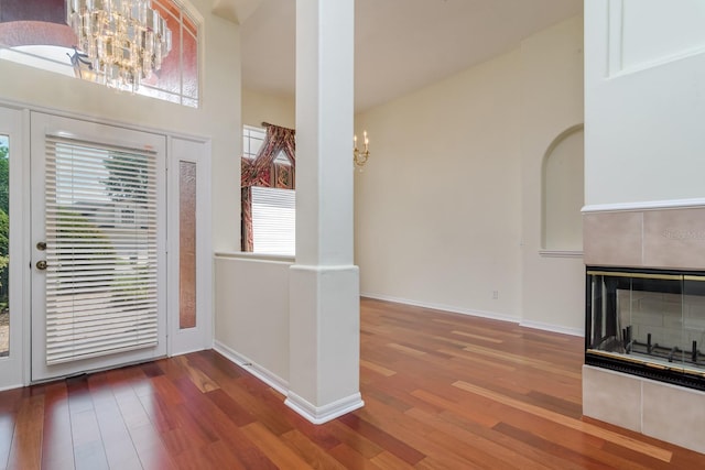 foyer with baseboards, wood finished floors, a chandelier, and a fireplace