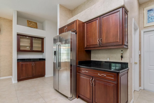 kitchen with stainless steel fridge, light tile patterned floors, baseboards, and glass insert cabinets