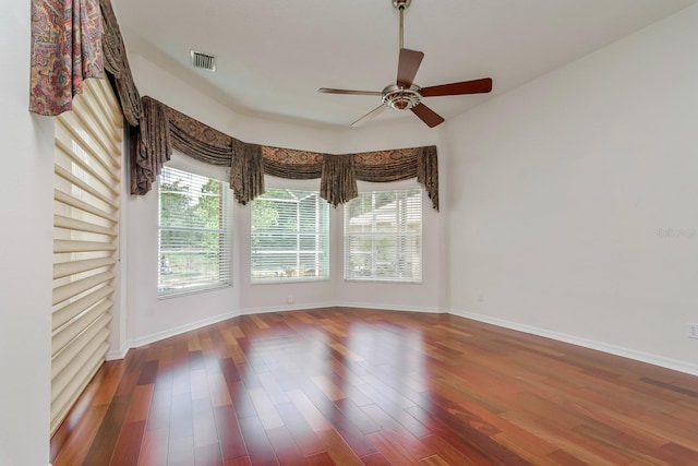 spare room featuring a healthy amount of sunlight, baseboards, ceiling fan, and wood finished floors
