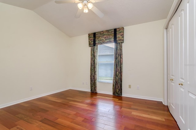unfurnished bedroom with a ceiling fan, wood finished floors, baseboards, a closet, and lofted ceiling