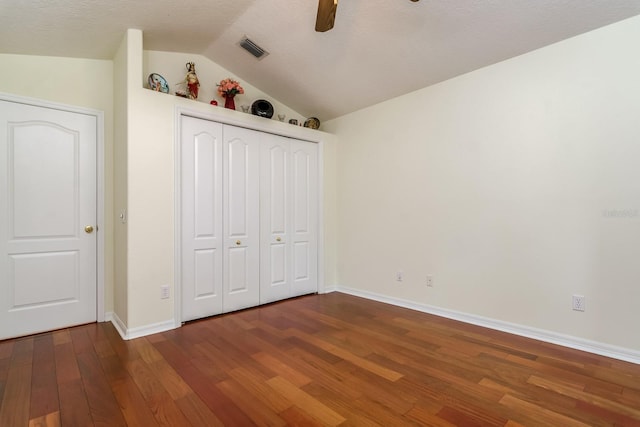 unfurnished bedroom with a ceiling fan, baseboards, wood finished floors, vaulted ceiling, and a closet