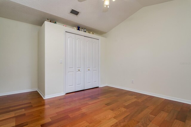 unfurnished bedroom with visible vents, vaulted ceiling, wood finished floors, baseboards, and a closet