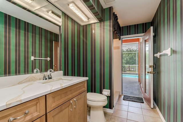 bathroom with tile patterned flooring, vanity, toilet, baseboards, and wallpapered walls
