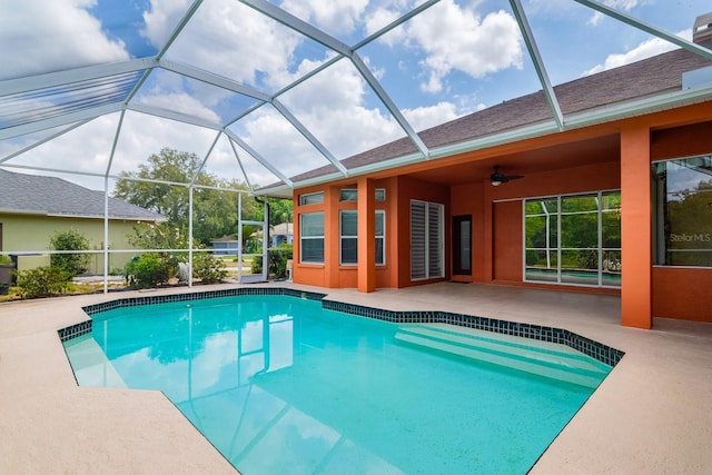 pool featuring glass enclosure, a patio, and a ceiling fan