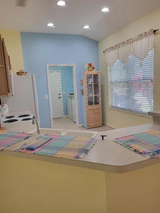 interior space with recessed lighting, baseboards, vaulted ceiling, tile patterned floors, and washing machine and clothes dryer