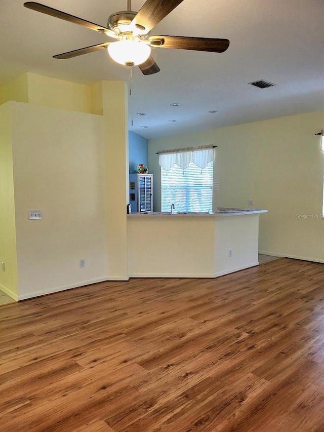 spare room featuring a ceiling fan, visible vents, a sink, and wood finished floors