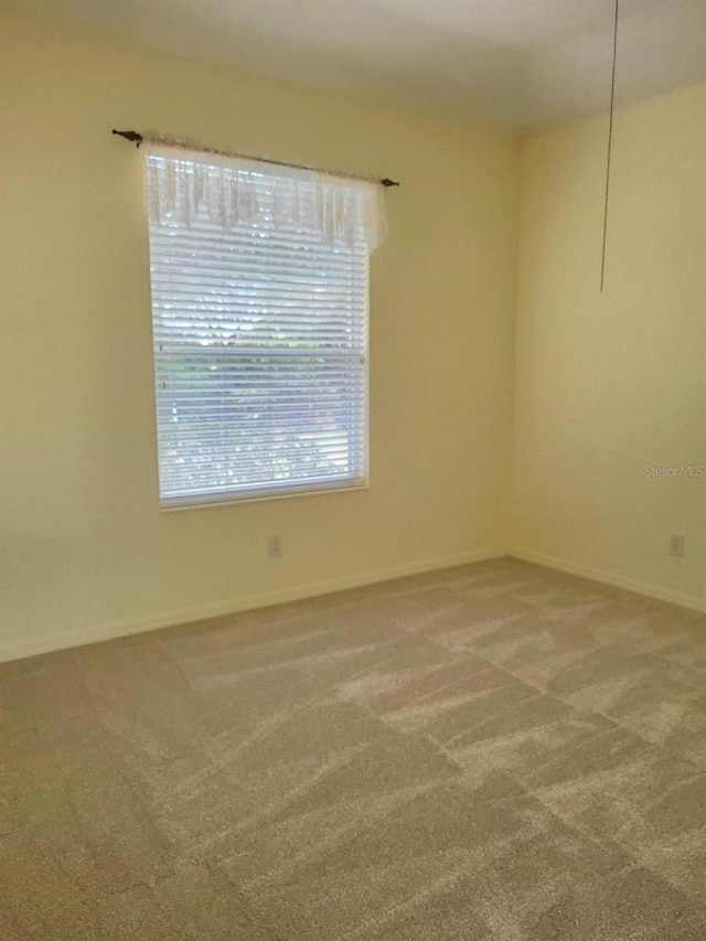 carpeted empty room featuring baseboards