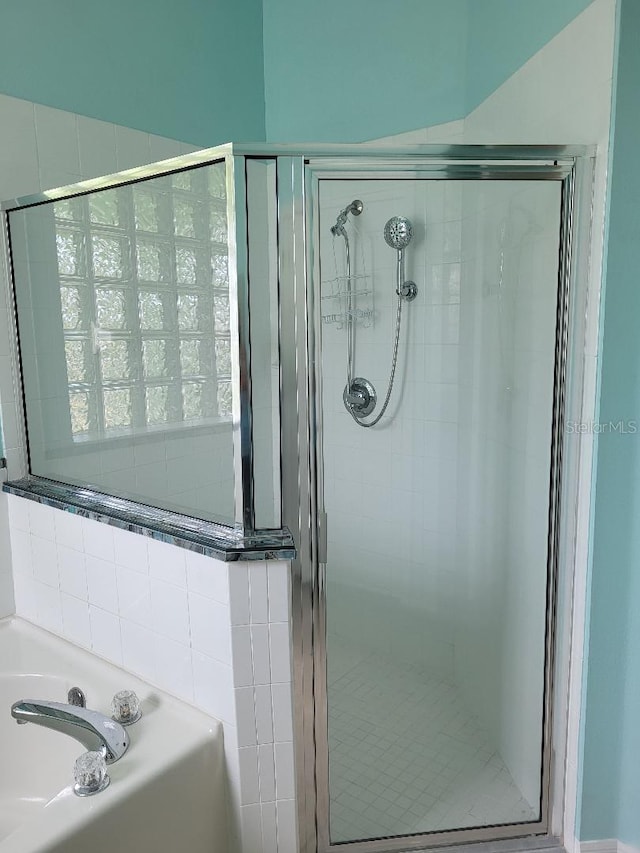 bathroom featuring a garden tub and a shower stall