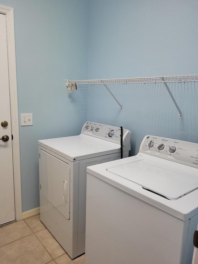 laundry area with washing machine and dryer, laundry area, baseboards, and light tile patterned floors