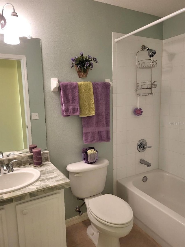 bathroom featuring tile patterned flooring, toilet, vanity, baseboards, and  shower combination