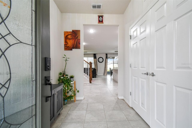 corridor featuring baseboards, stairs, visible vents, and light tile patterned flooring