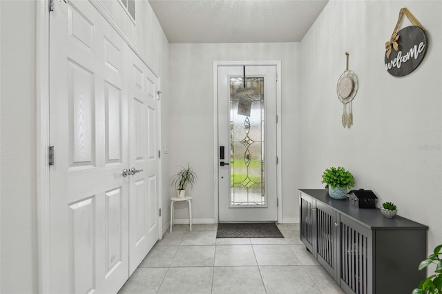 entryway featuring light tile patterned floors, a textured ceiling, and baseboards