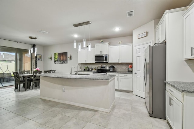 kitchen featuring light stone counters, stainless steel appliances, a sink, white cabinets, and decorative backsplash