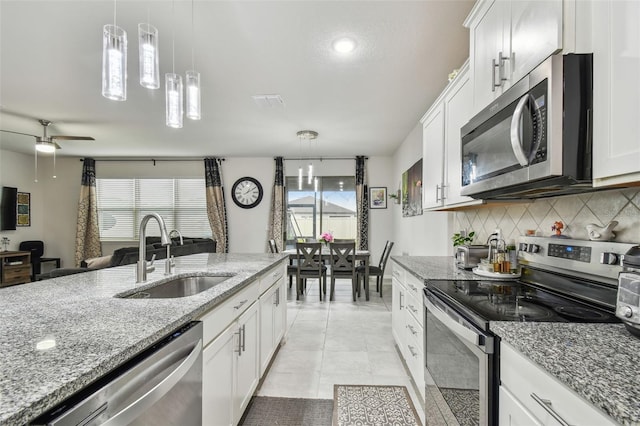 kitchen featuring stainless steel appliances, backsplash, a sink, and white cabinets