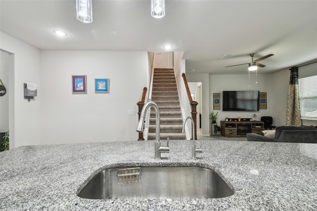 kitchen featuring a ceiling fan, visible vents, light stone counters, and a sink