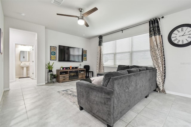 living area featuring ceiling fan, light tile patterned flooring, visible vents, and baseboards