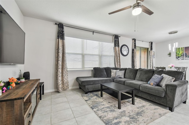 living room with ceiling fan, baseboards, and light tile patterned floors