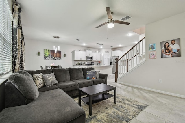 living room featuring baseboards, visible vents, ceiling fan, stairway, and light tile patterned flooring