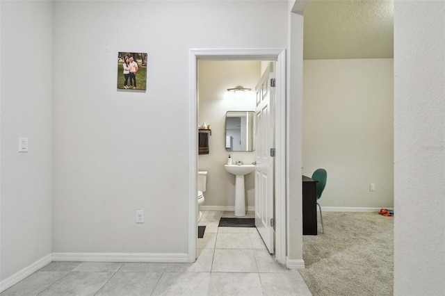 hall featuring tile patterned flooring and baseboards