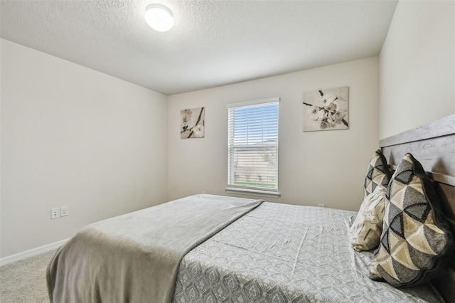 bedroom with a textured ceiling, carpet floors, and baseboards