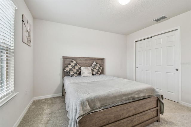 bedroom featuring light colored carpet, visible vents, a textured ceiling, and baseboards