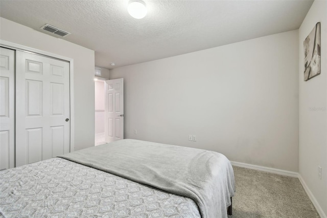 bedroom featuring a closet, visible vents, carpet flooring, a textured ceiling, and baseboards