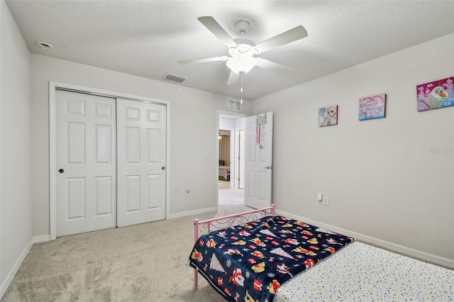 carpeted bedroom with a closet, visible vents, a textured ceiling, and baseboards