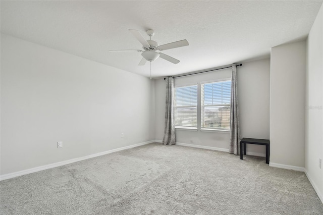 carpeted spare room with ceiling fan, a textured ceiling, and baseboards